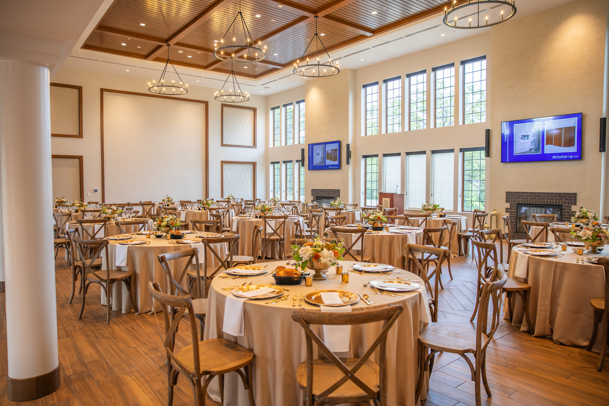 Elegant banquet hall setup featuring round tables with golden tableware and a large window wall. Ideal for events and gatherings.