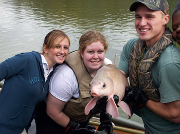 Three individuals together holding a fish