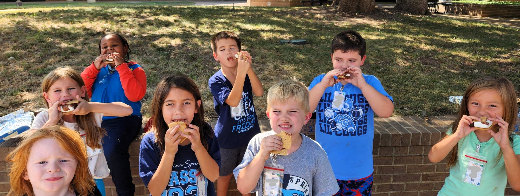 Image of Kids College Friday children sharing s'mores they made in class and smiling.