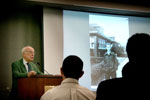 Watson giving speech with 2 people in view listening