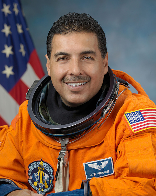 Portrait of astronaut José Hernández in a space suit, featuring the American flag and NASA insignia.