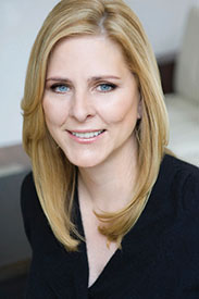 Professional headshot of a woman with long blonde hair and blue eyes, smiling warmly.