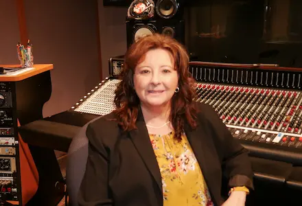 Kayla Rosas sitting in front of a audio sound board