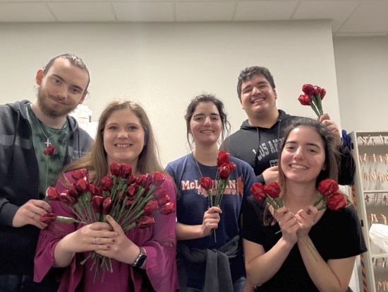 PTK members smile and pose holding candy-filled roses