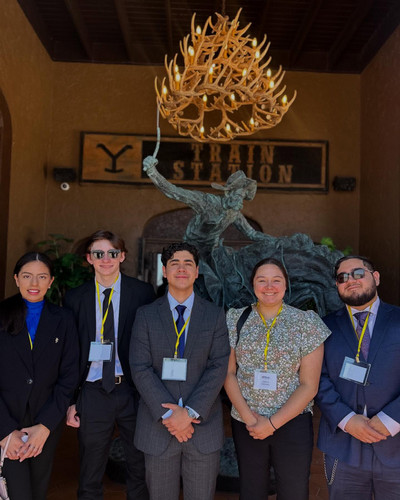 Student government members in professional dress posing in front of a statue